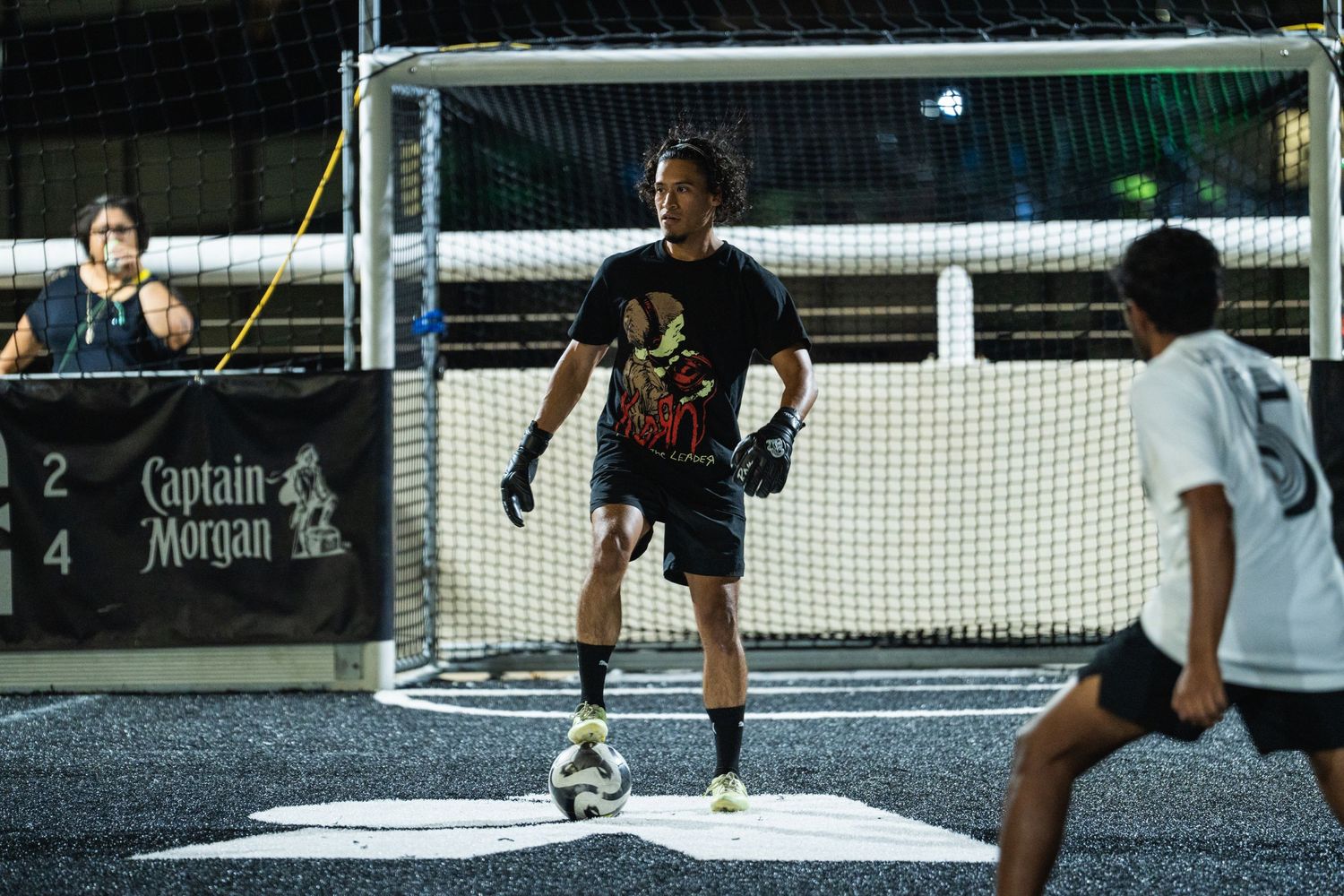 Soccer goalkeeper preparing to defend the net during a nighttime match.