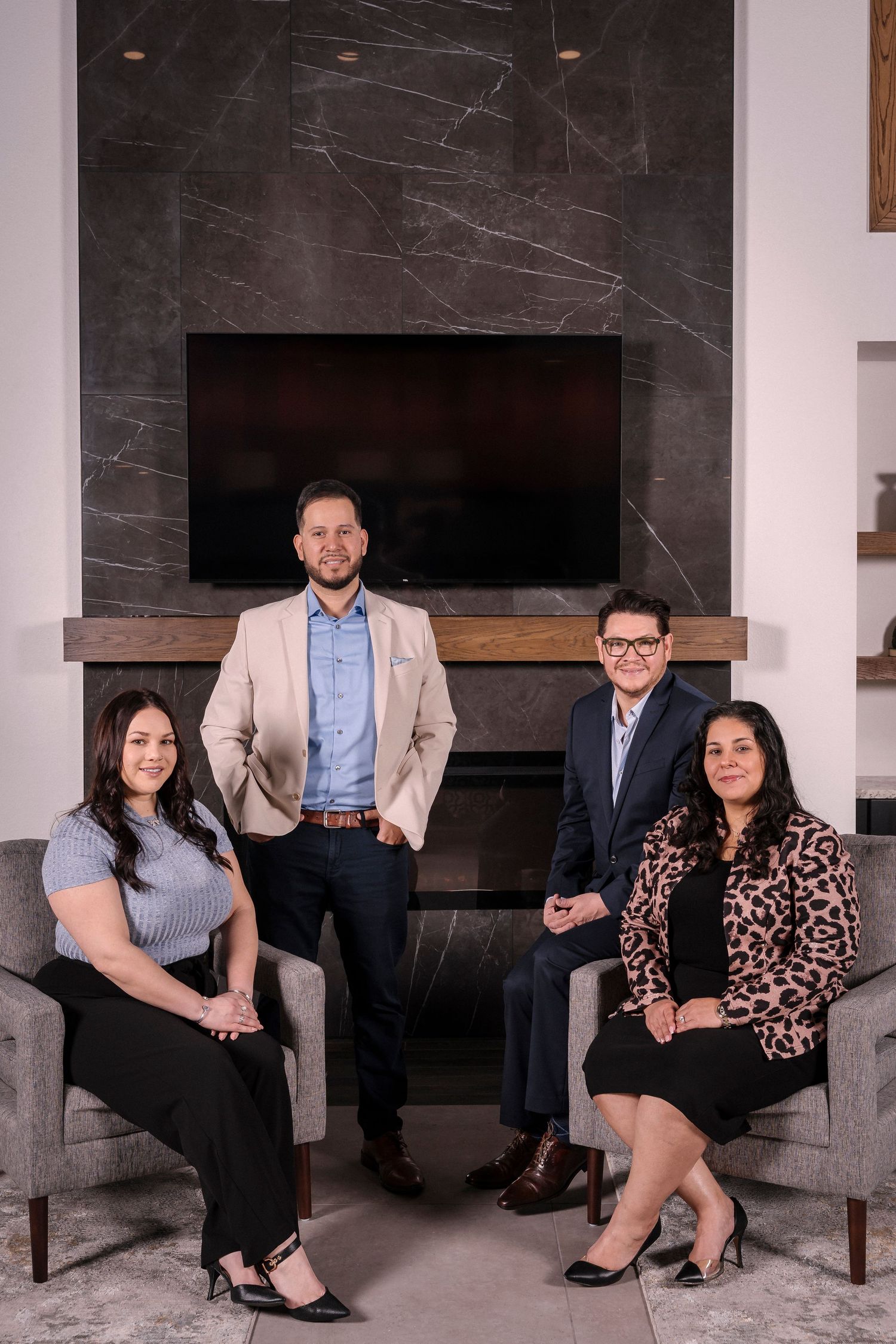 Professional business team seated around a modern marble fireplace in an elegant office setting.