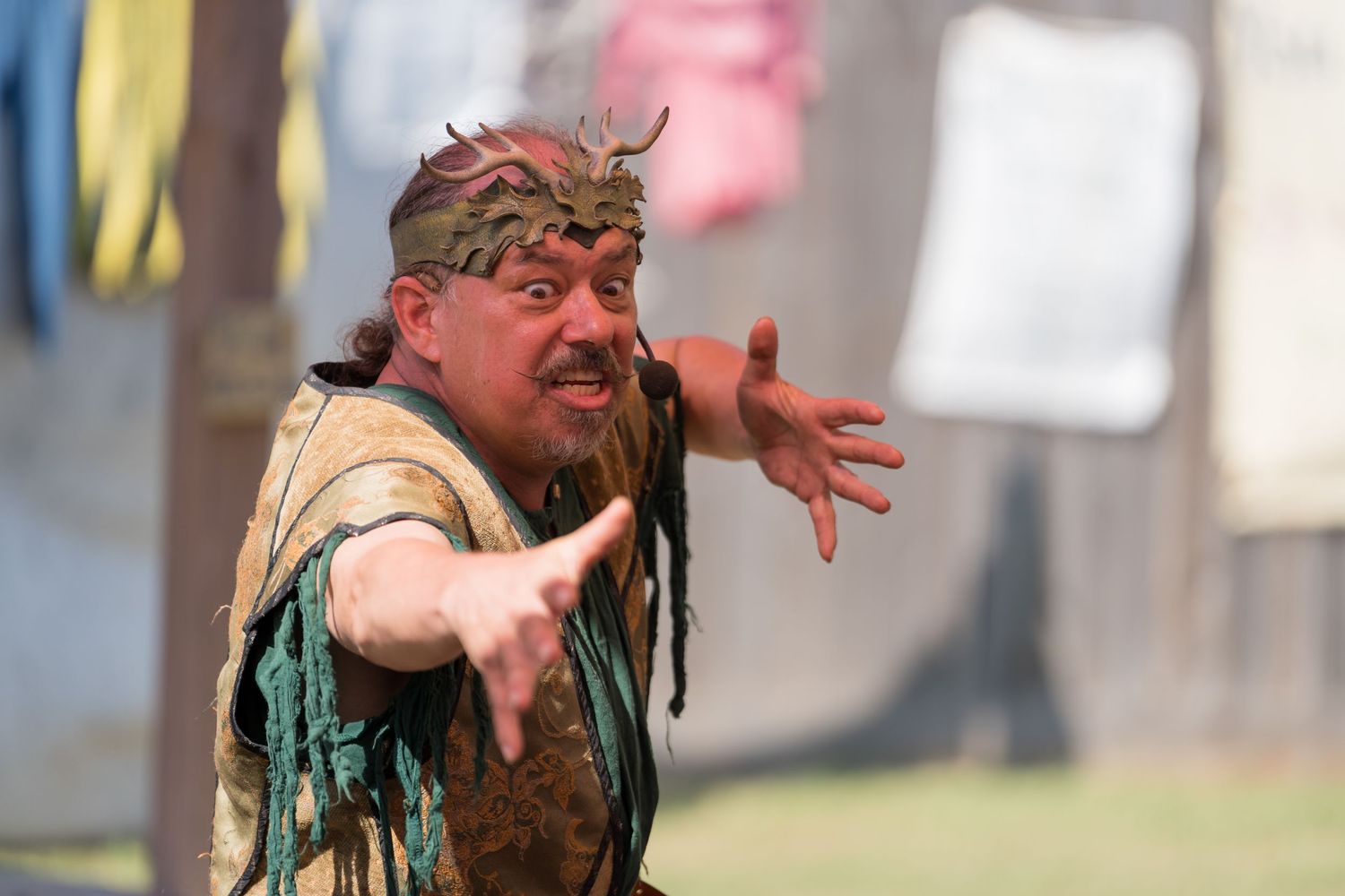 A costumed performer gestures dramatically during an outdoor renaissance festival performance.