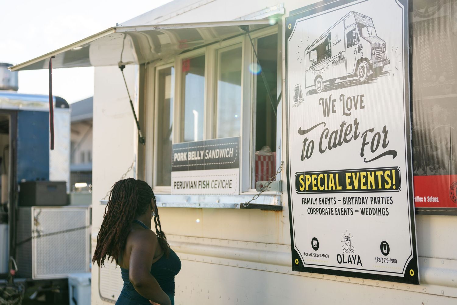 Customer approaching food truck window with special events sign.