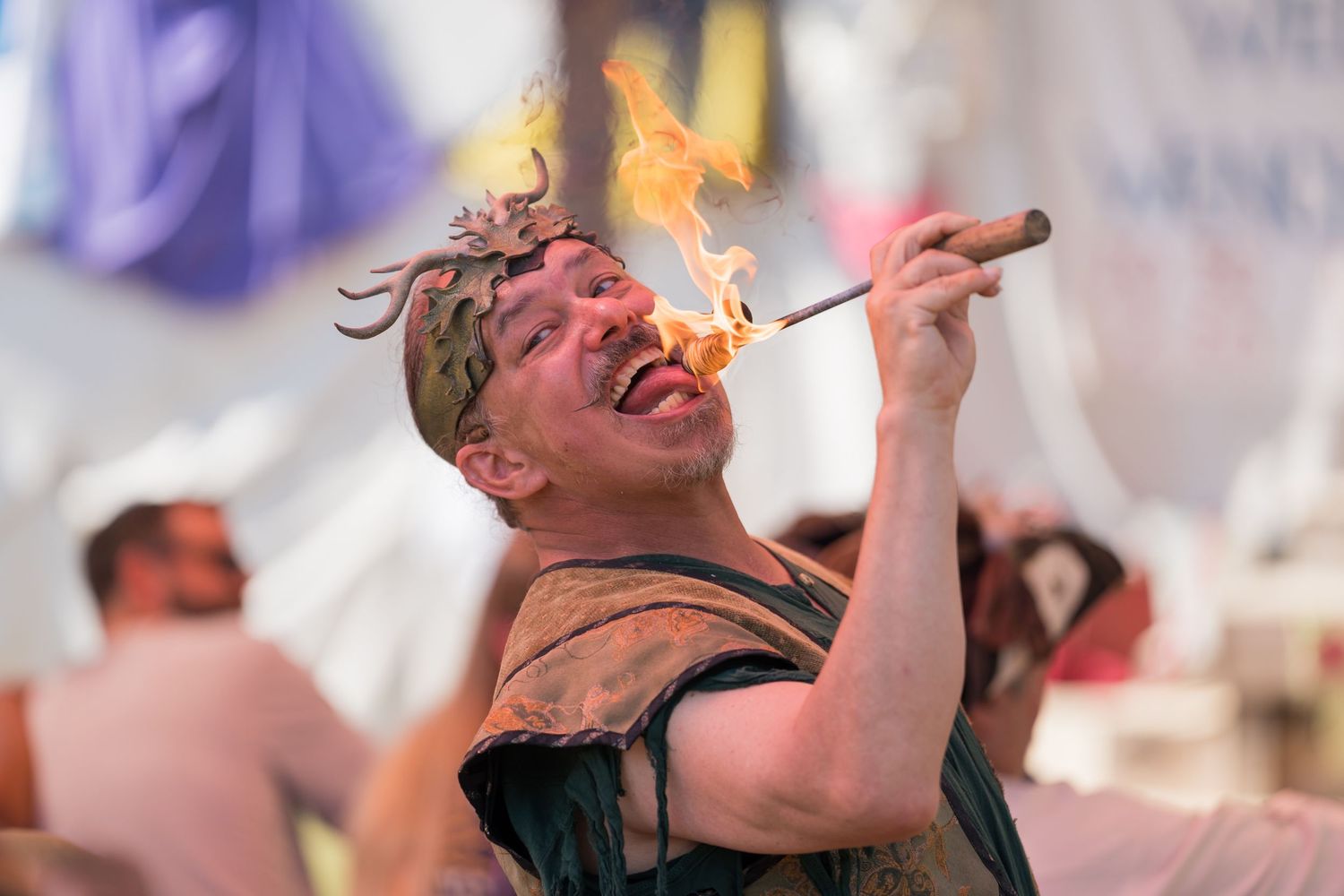 A fire breather performs a dangerous flame stunt at a renaissance festival.