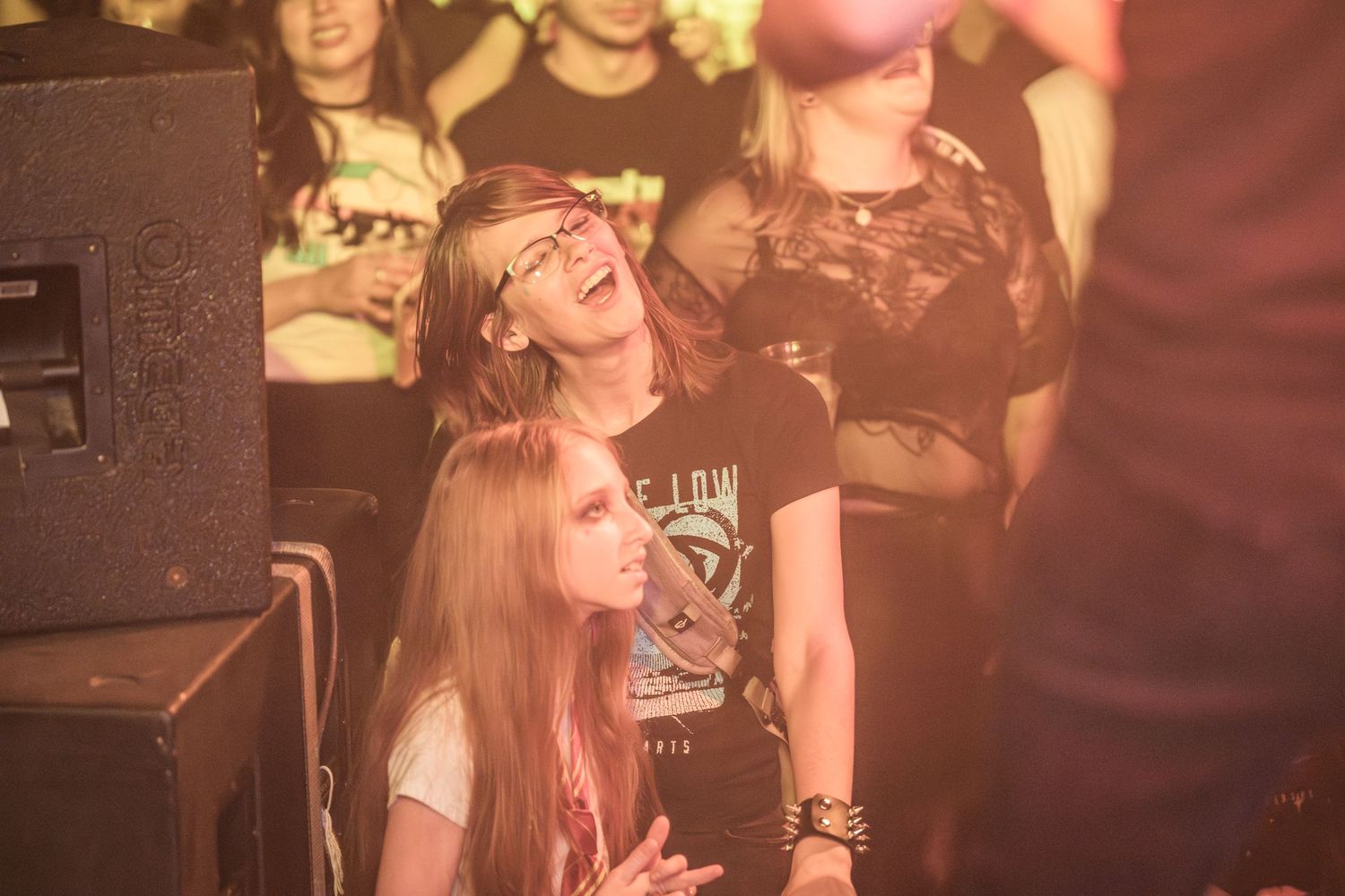 Concert attendees enjoying the atmosphere during a live performance with warm lighting at a music venue.