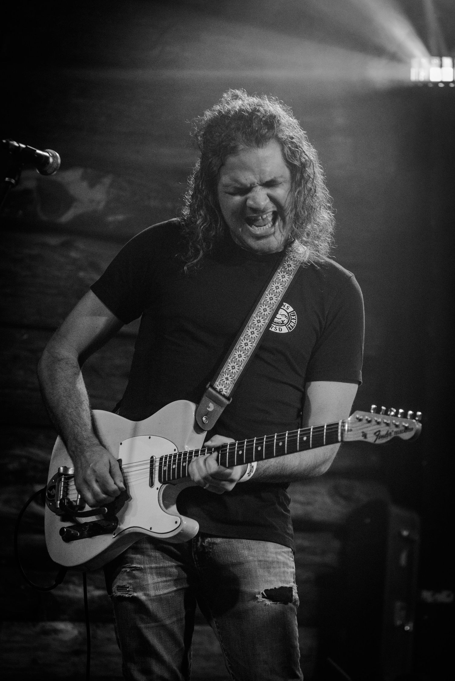 An energetic guitarist plays a white electric guitar during an intense performance moment.