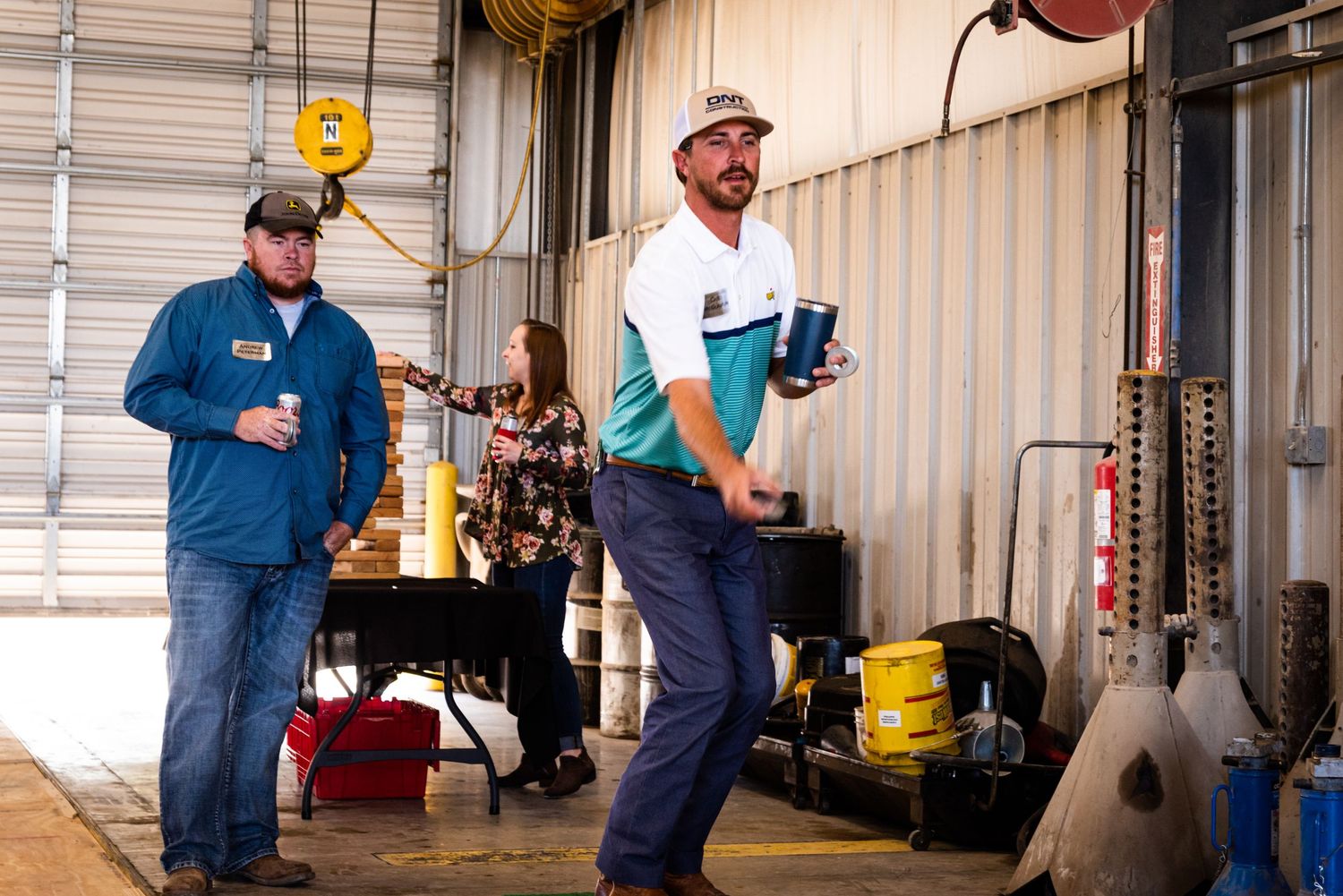 People gathered in a warehouse setting holding drinks.