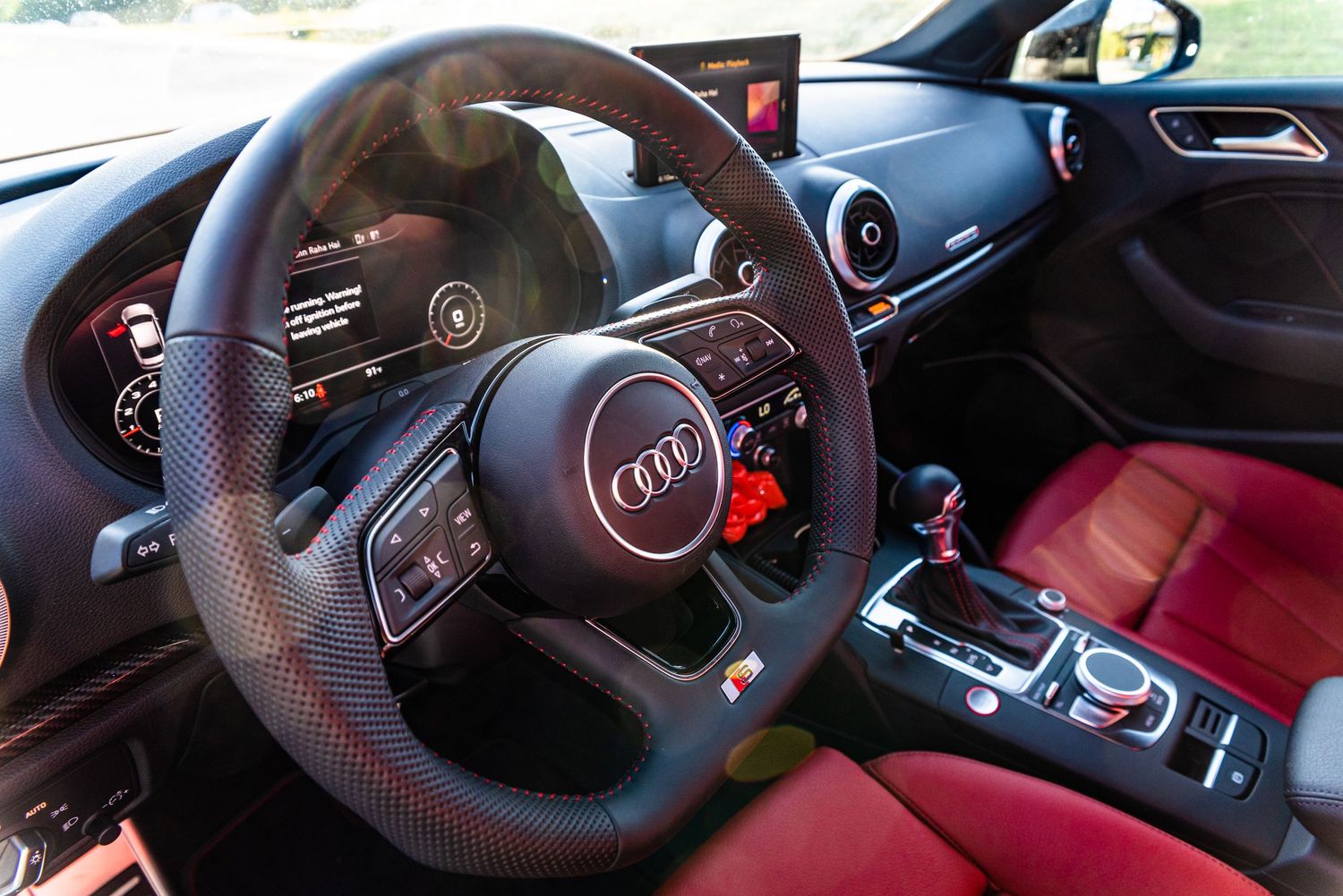 Interior view of an Audi sports car showing red leather seats and modern dashboard controls.