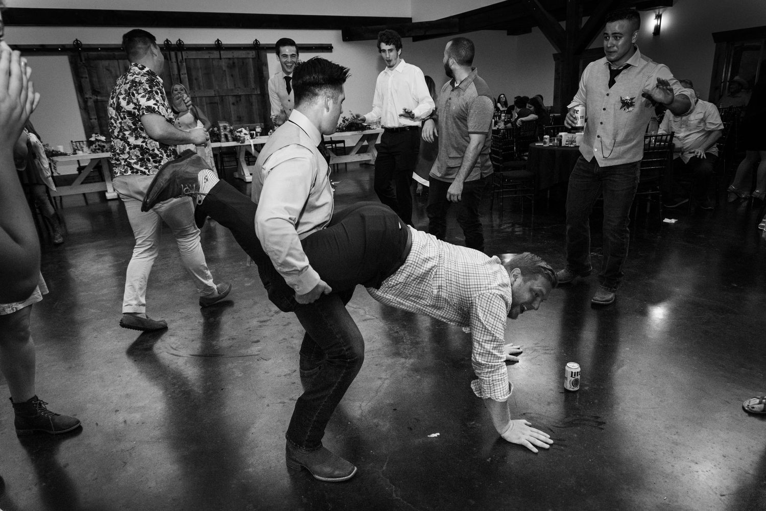 Wedding guests dance energetically on the reception dance floor in black and white.