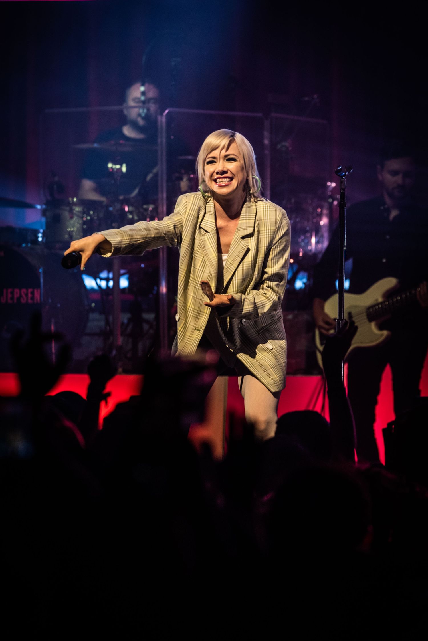 Energetic stage performance with band members and dramatic red lighting effects.