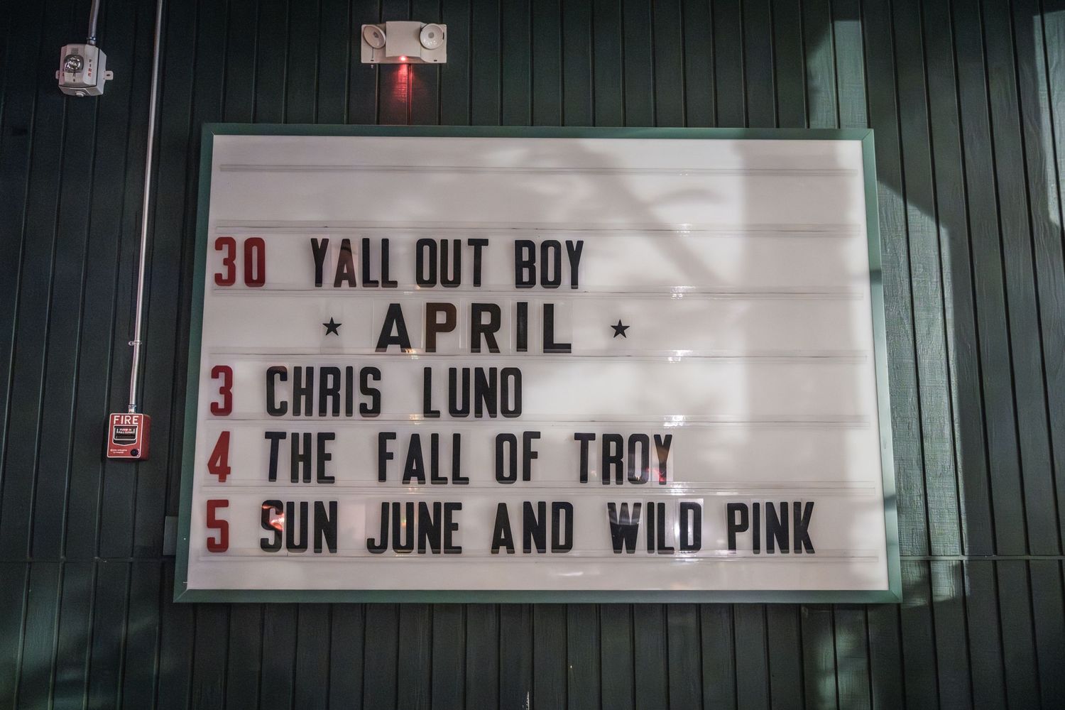 A venue marquee board displays upcoming show dates including Fall Out Boy and other artists.