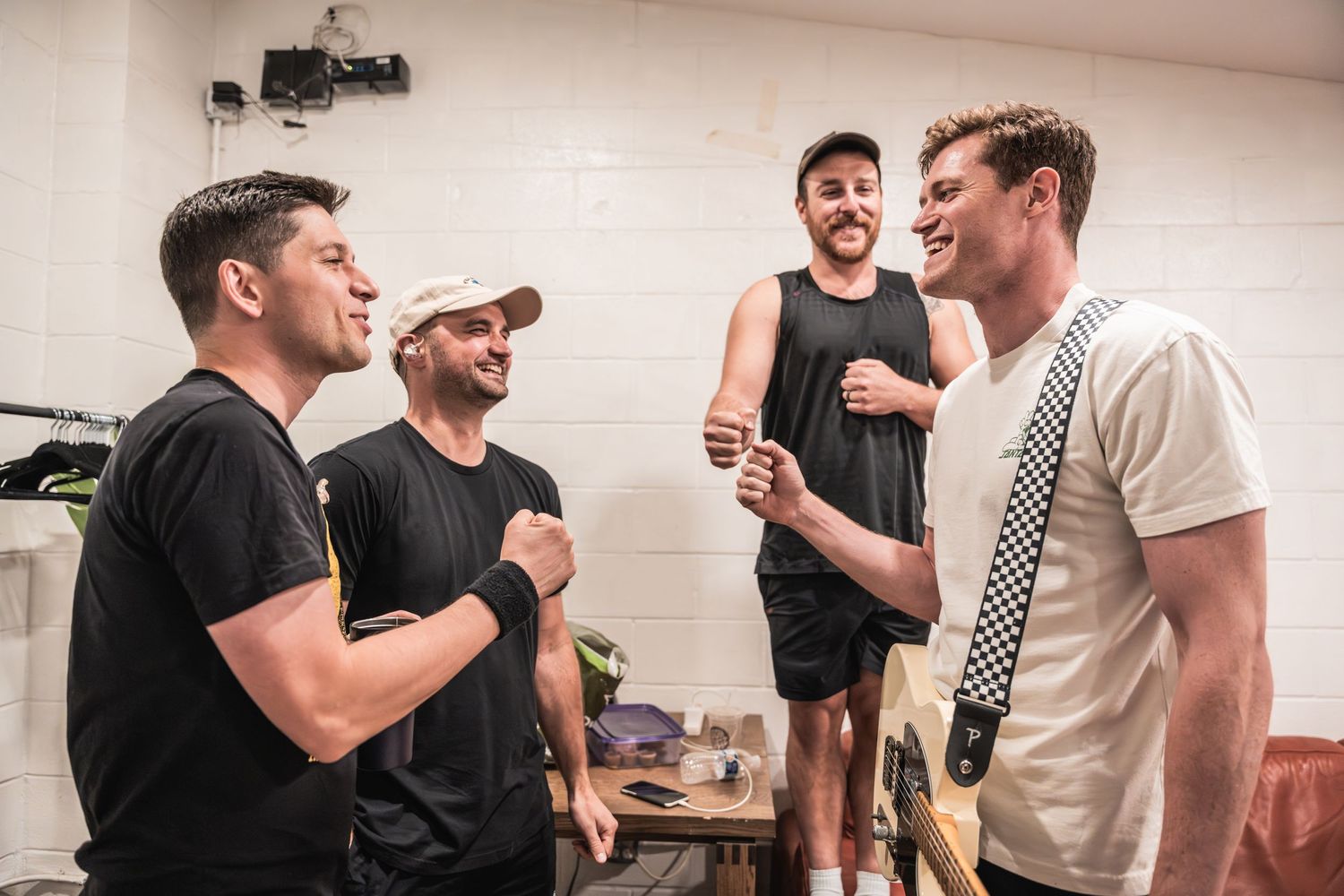 Group sharing laughs in bright backstage dressing room before performance.