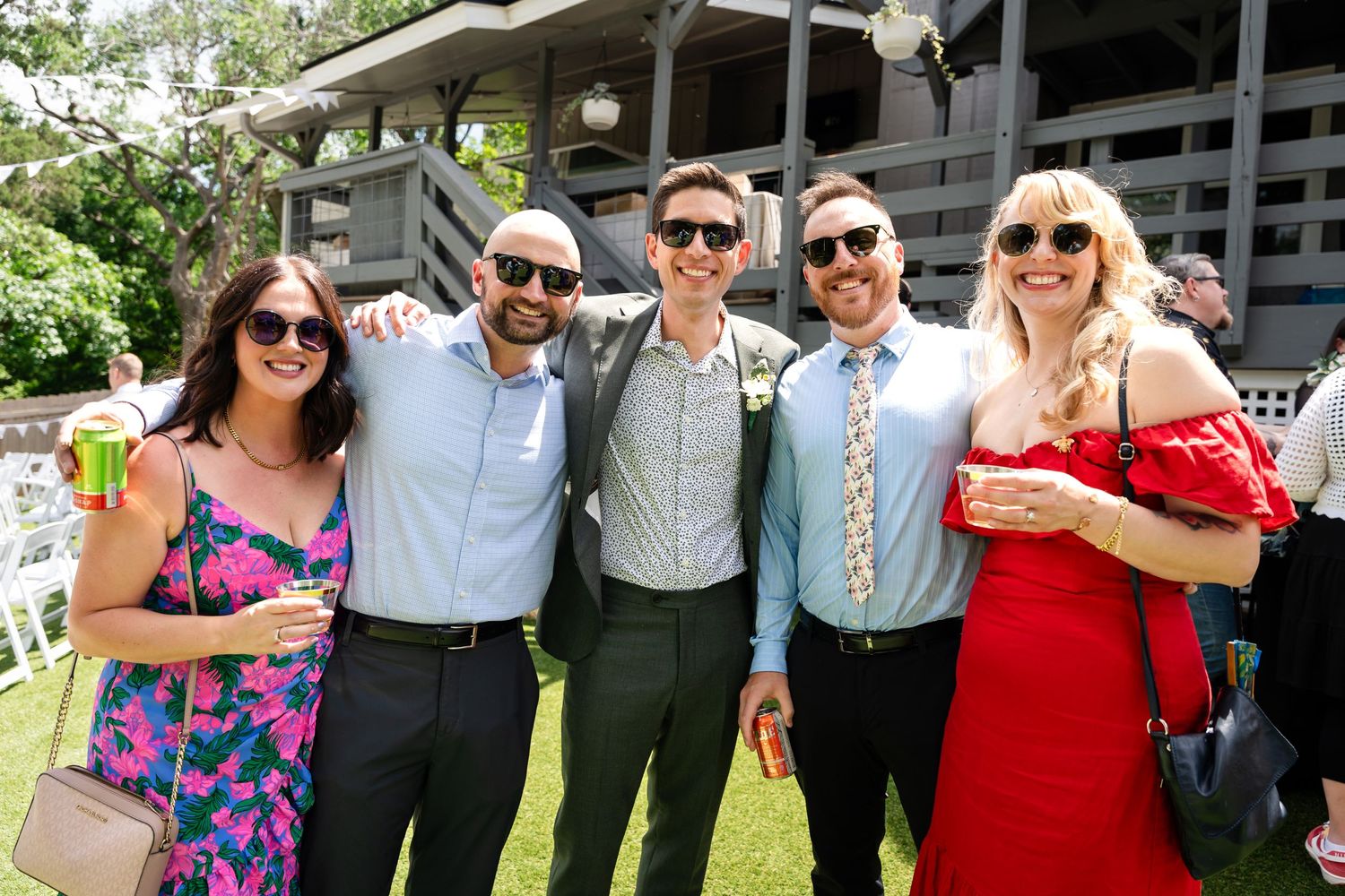 Wedding guests in colorful attire posing together at outdoor reception.