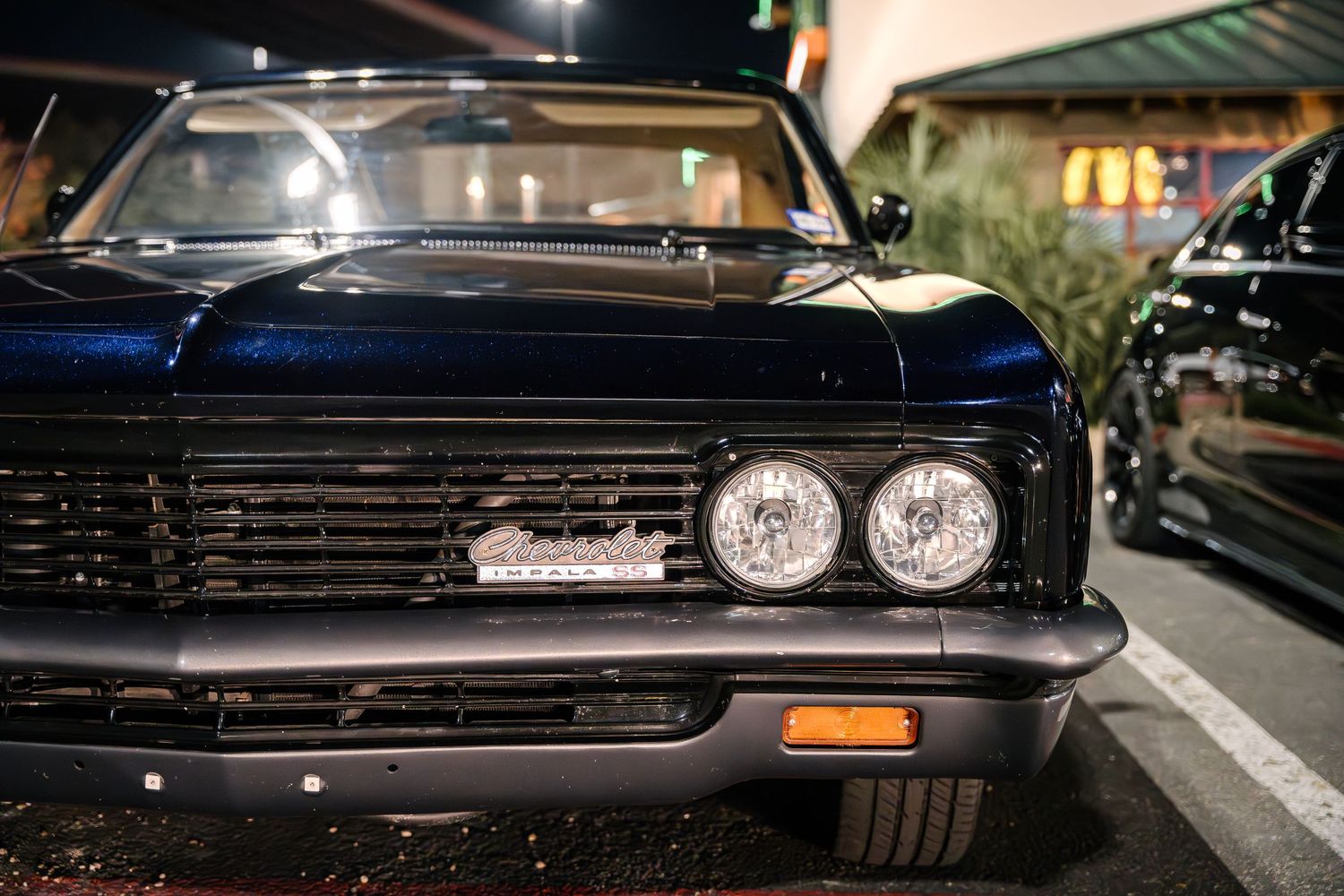 Close-up front view of a classic black car showing dual headlights and chrome grill.