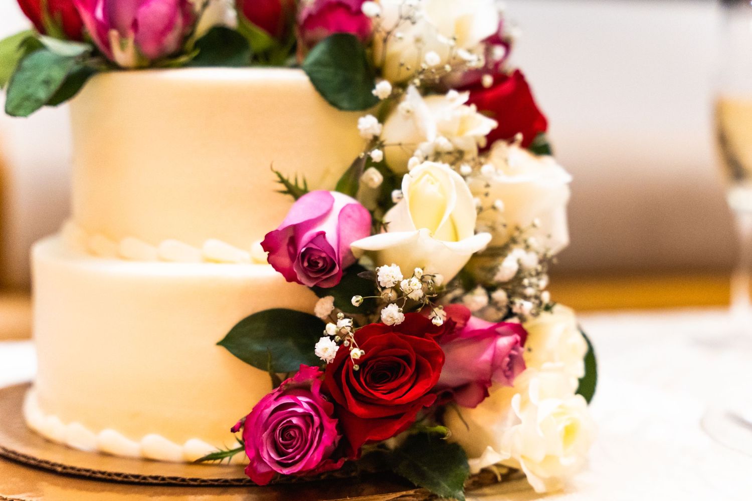 Close-up of elegant wedding cake decorated with fresh pink and white roses.