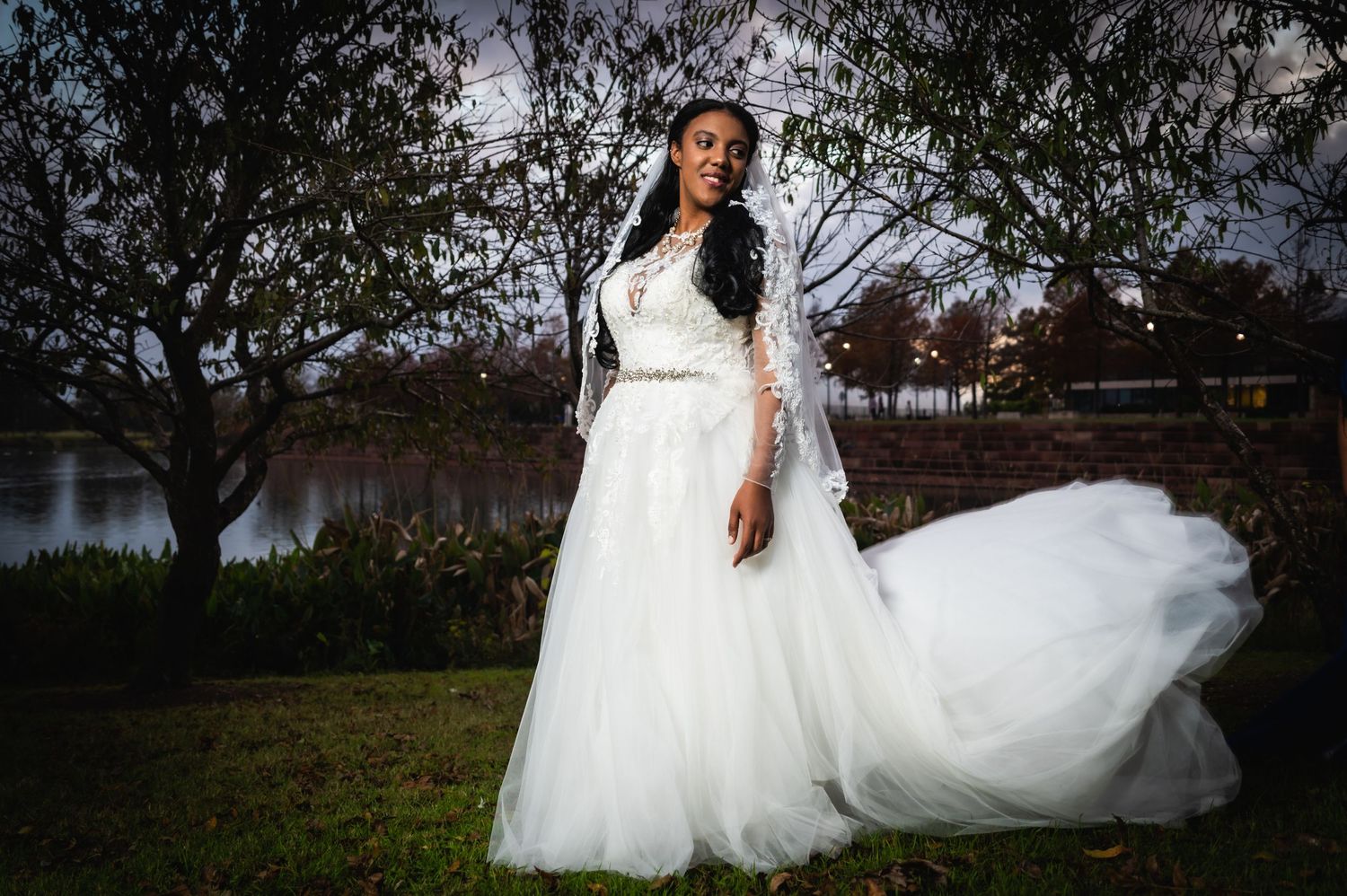 A flowing white wedding dress billows in the breeze against a dusky outdoor setting.