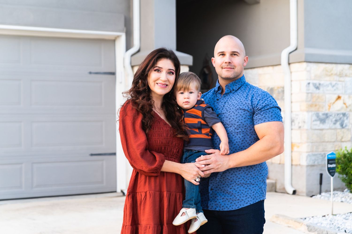 Fall family portrait in front of garage door with coordinated outfits.
