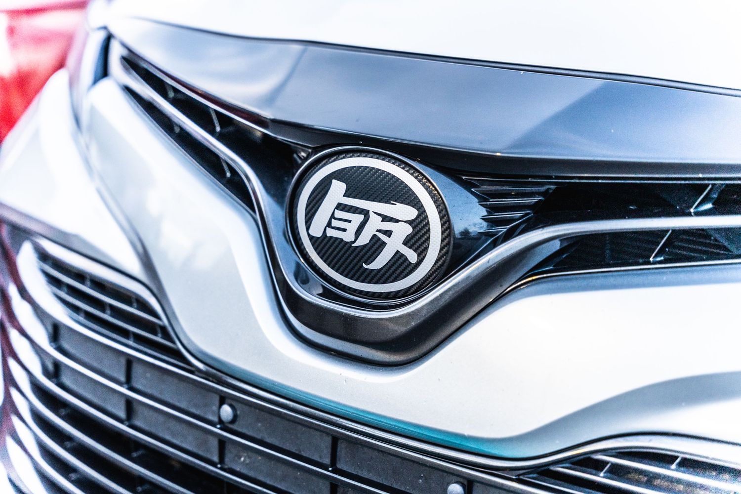 Chrome Toyota logo and grille detail on a modern vehicle front end.