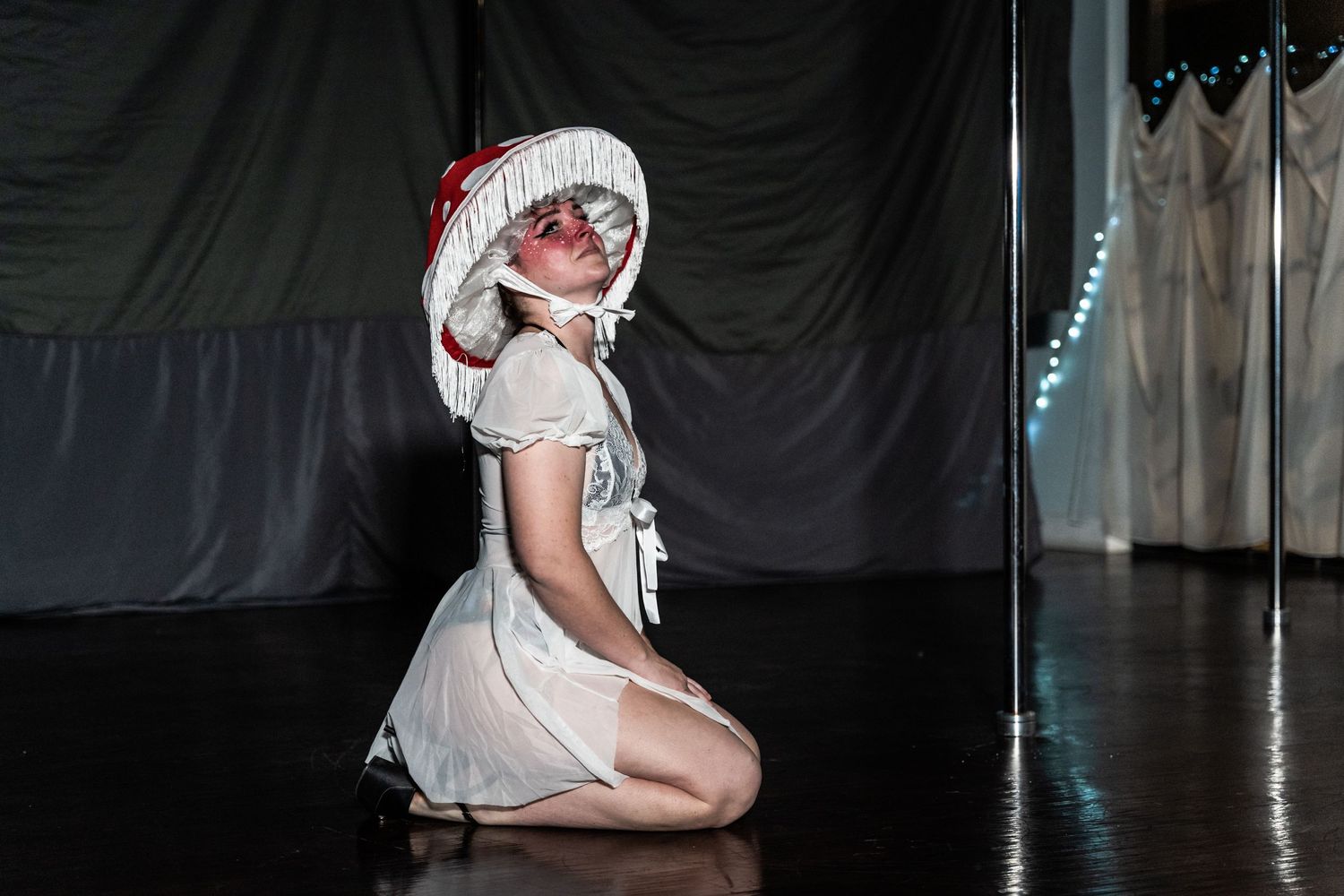 Performer in white costume posing on stage with theatrical lighting.