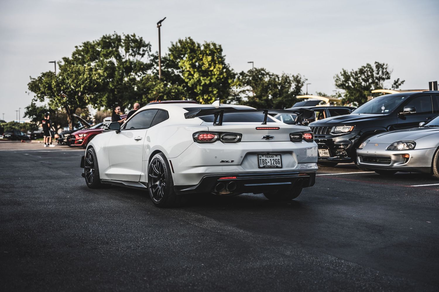 White Chevrolet Camaro with black accents parked in asphalt parking lot during daytime.