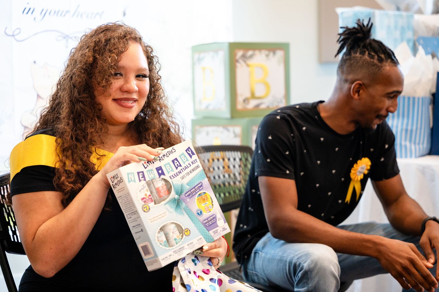 Two people looking at baby shower gifts during celebration.