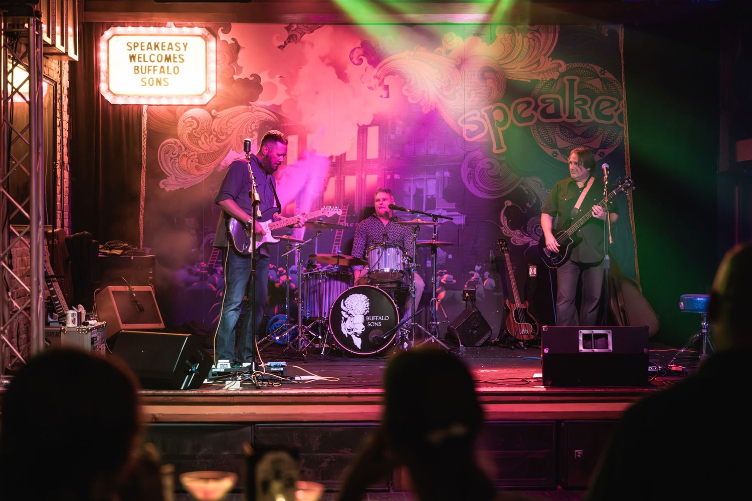 Band performing on stage with colorful lighting and music equipment.