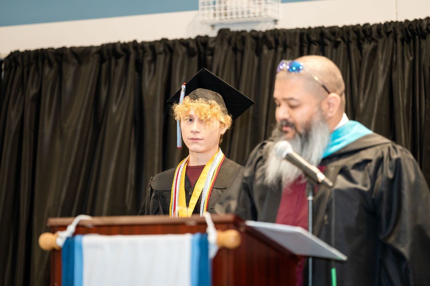 Graduate and faculty member stand together at podium during commencement ceremony.