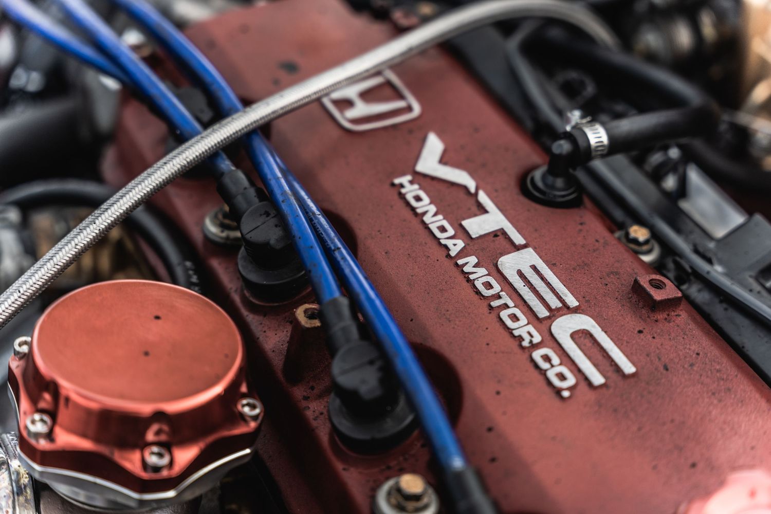 Close-up of a Honda VTEC engine cover with blue and red components visible.