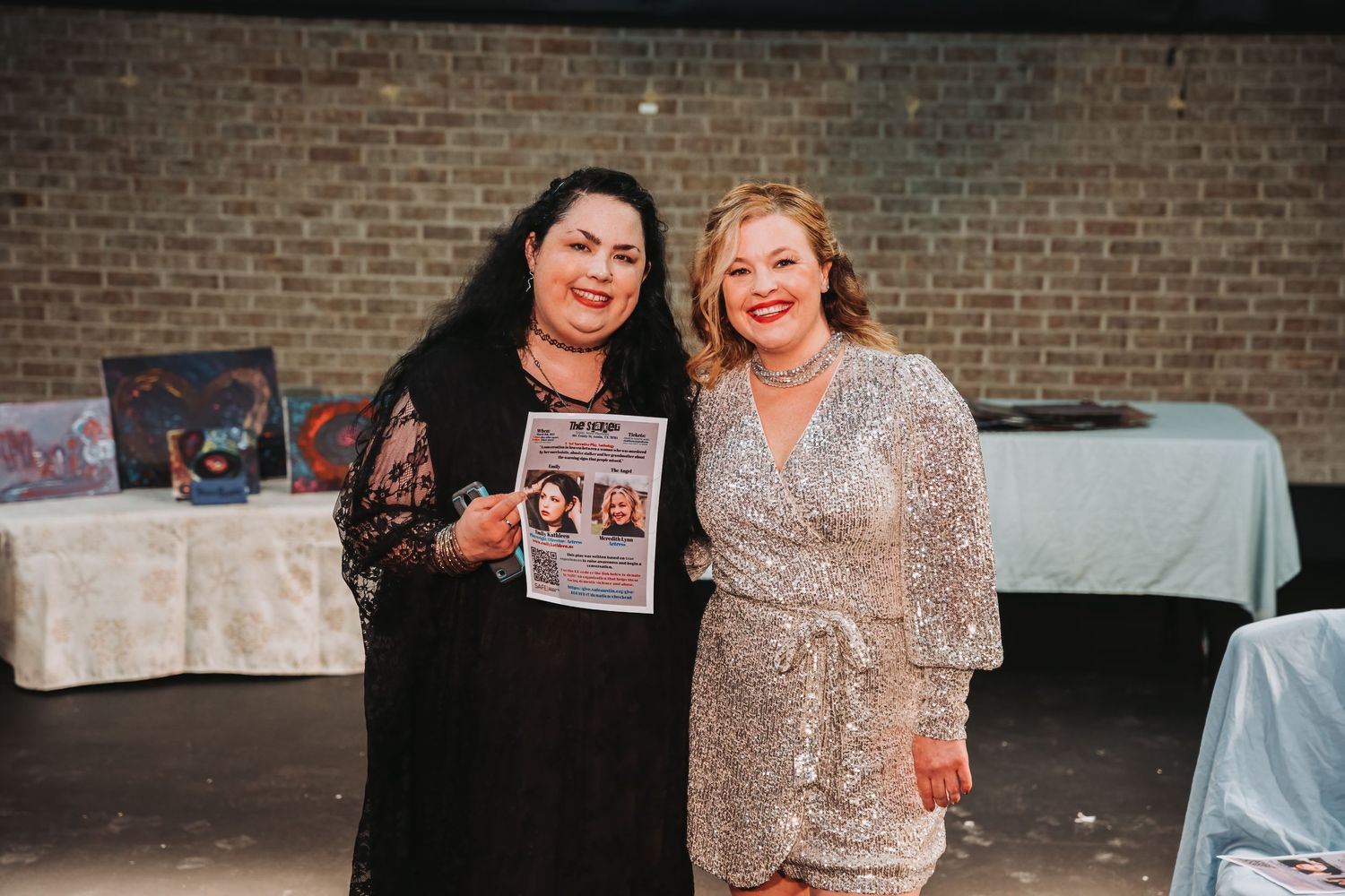 Two performers pose together holding a program during a theatrical production.