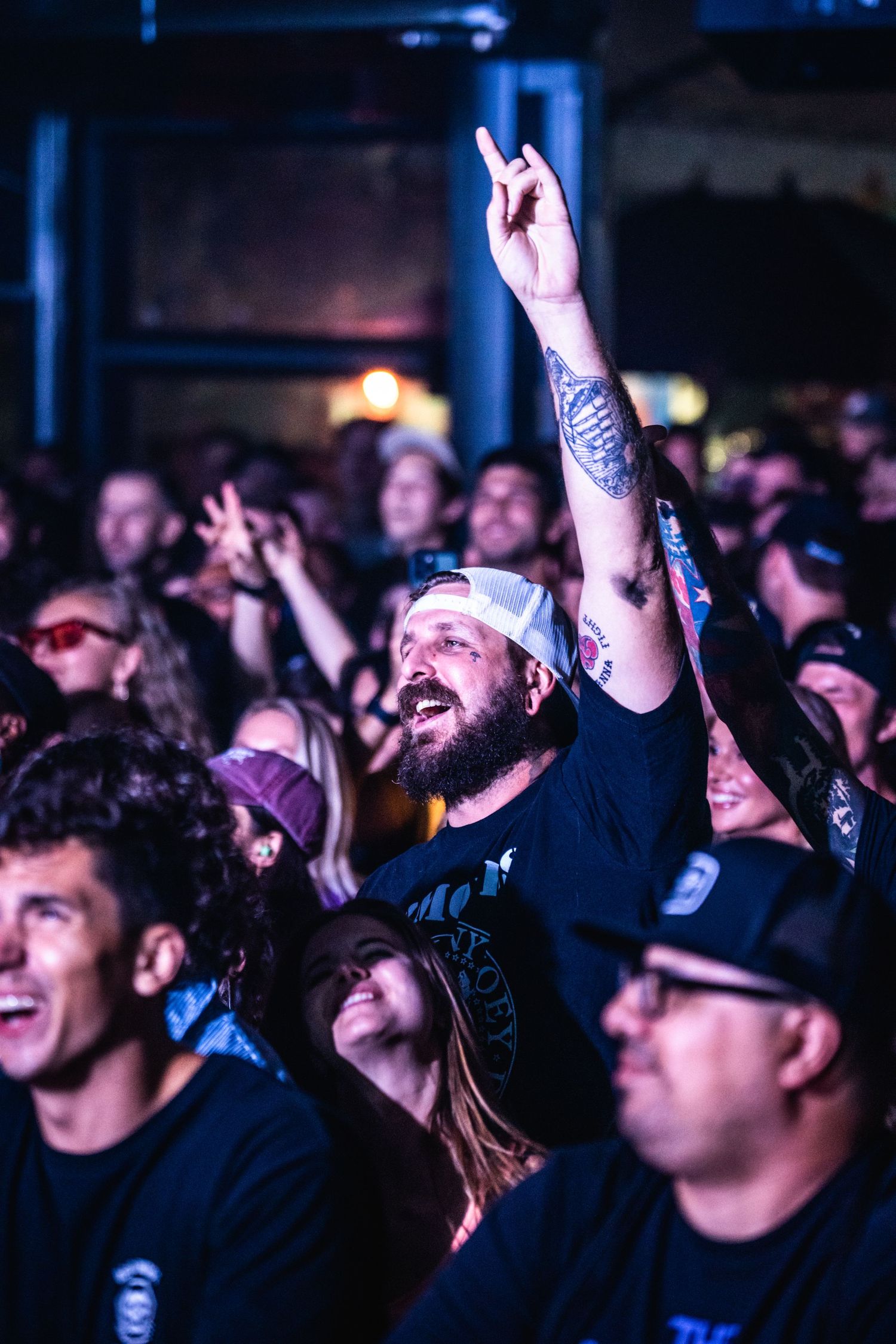 Concert attendee raises hand in excitement among crowd during live music performance.