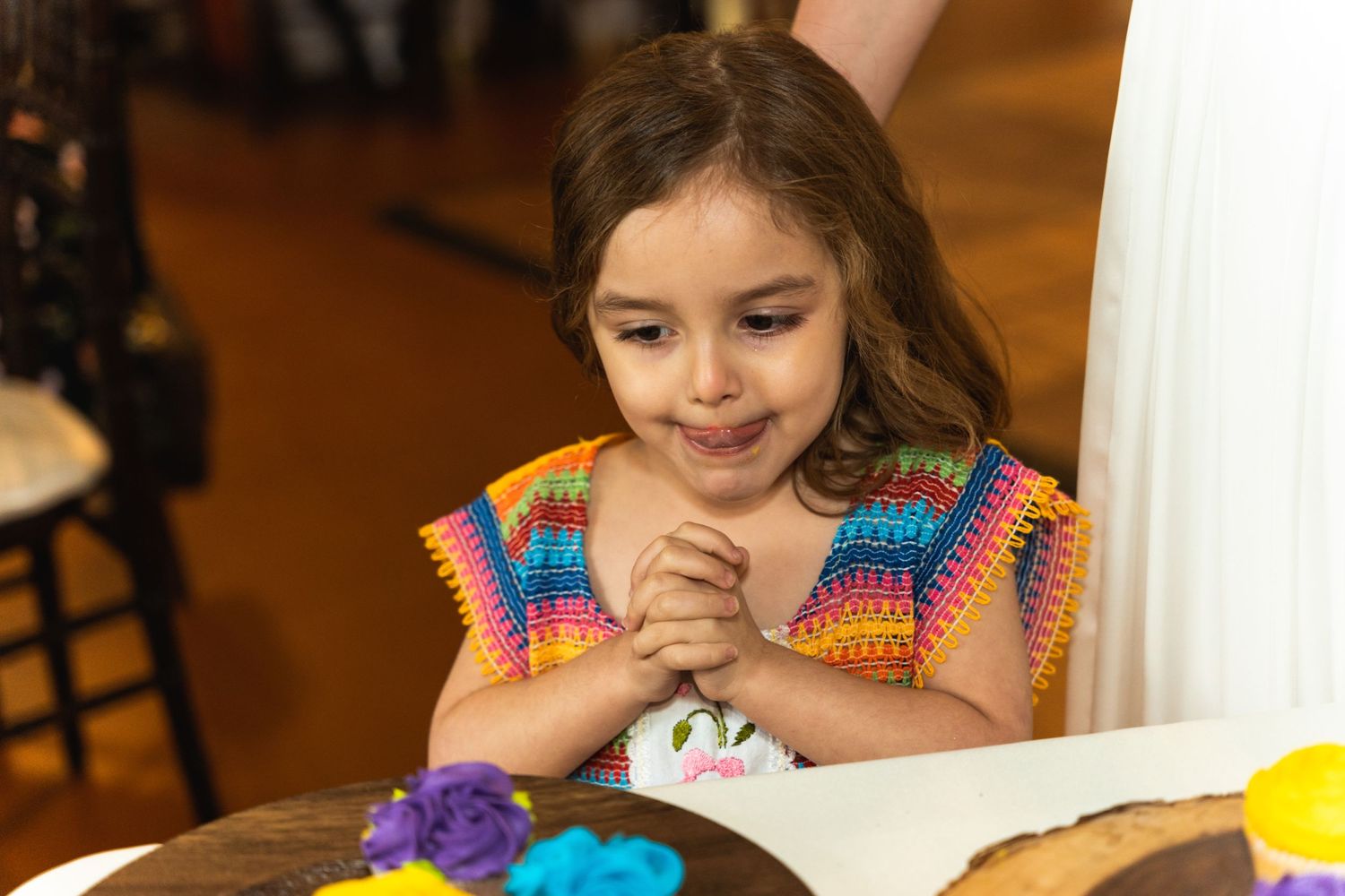 Young guest in colorful attire smiles while enjoying wedding reception activities.