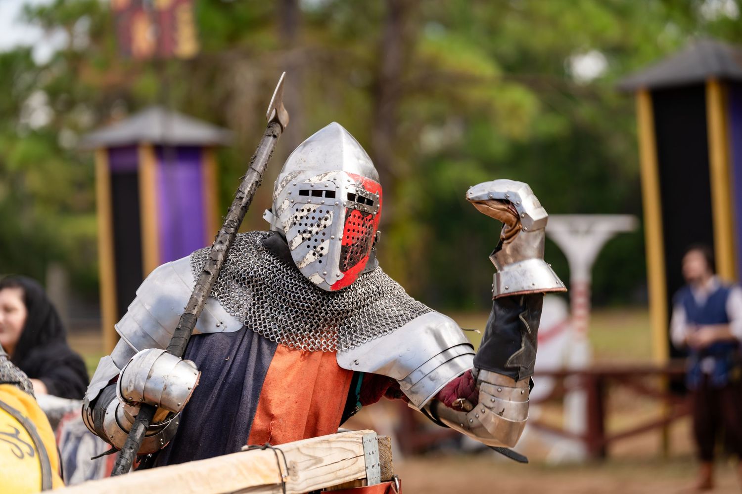 Medieval knights in armor and chainmail engage in sword combat at a historical reenactment event.