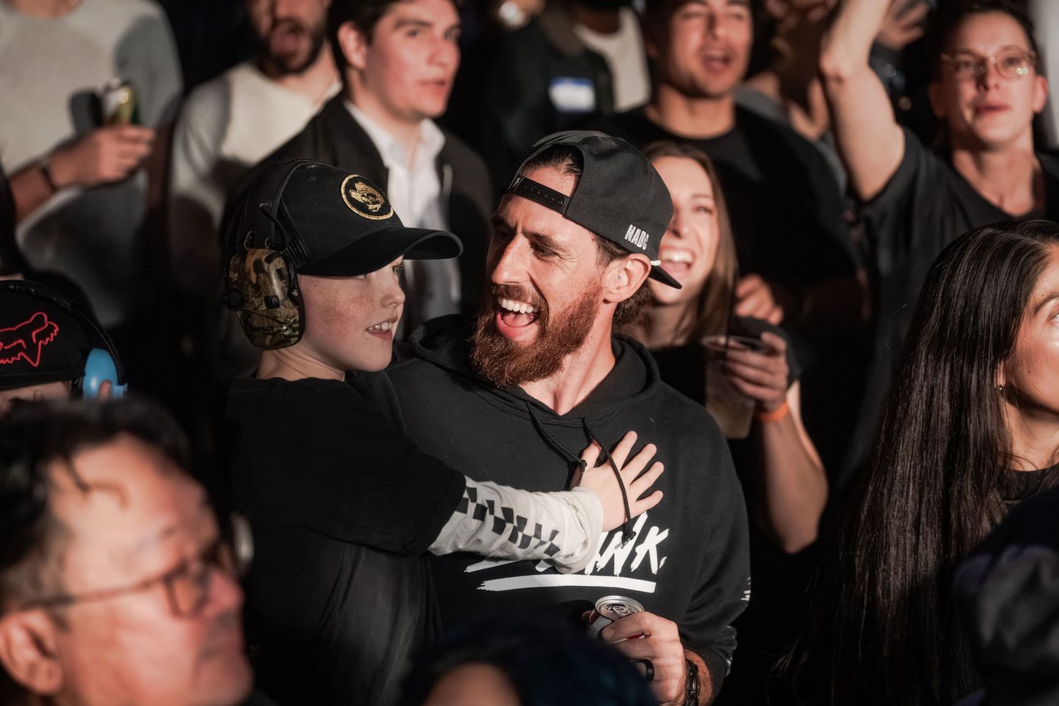 People enjoying a concert in a dark venue with animated expressions and reactions on their faces.