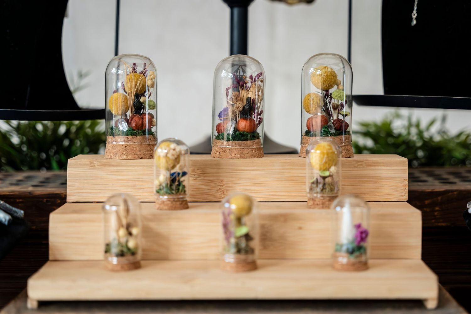 Rustic wooden dessert display with multiple tiers showcasing elegant wedding cakes and glass bell jar decorations.