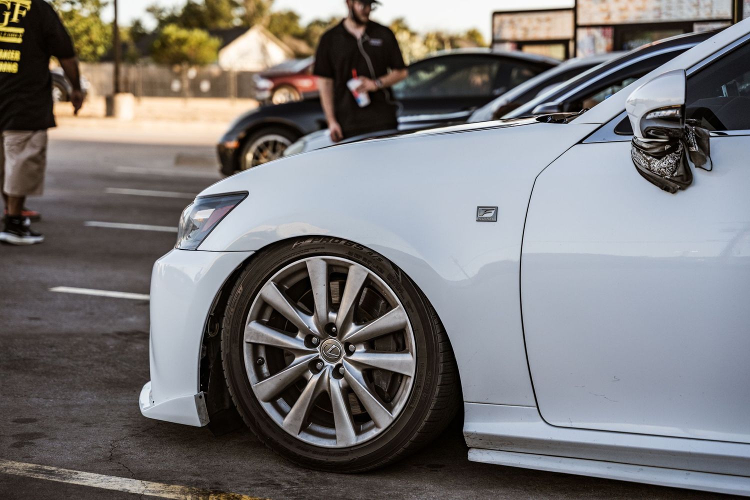 White sports car with custom alloy wheels and lowered suspension in a parking lot.