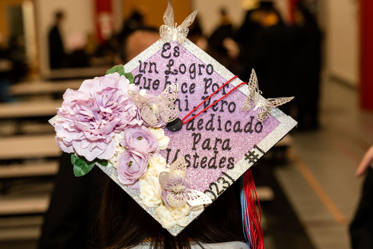 Decorated graduation cap with pink flowers and Spanish text.