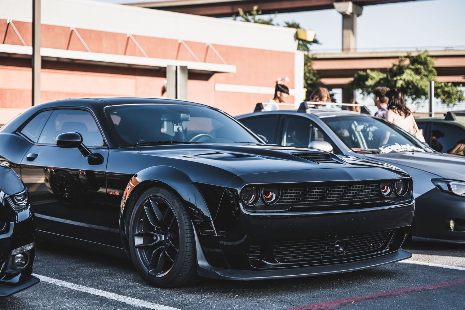 Black Dodge Challenger with aggressive body styling parked at car meet.