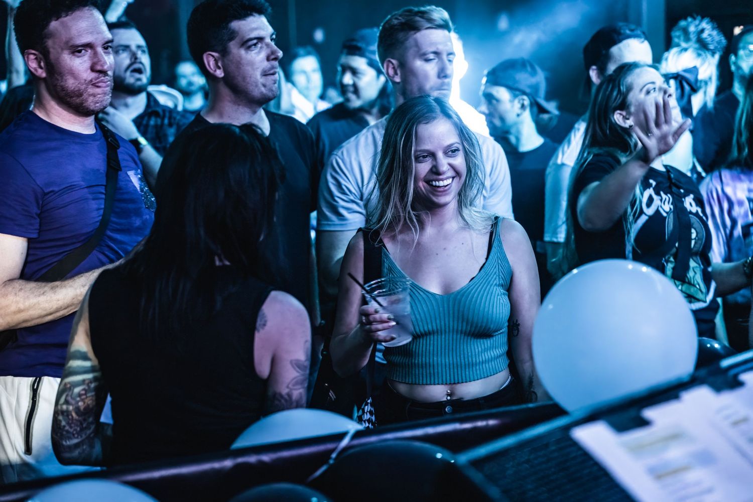 Energetic concert crowd enjoying live music performance with blue lighting effects.