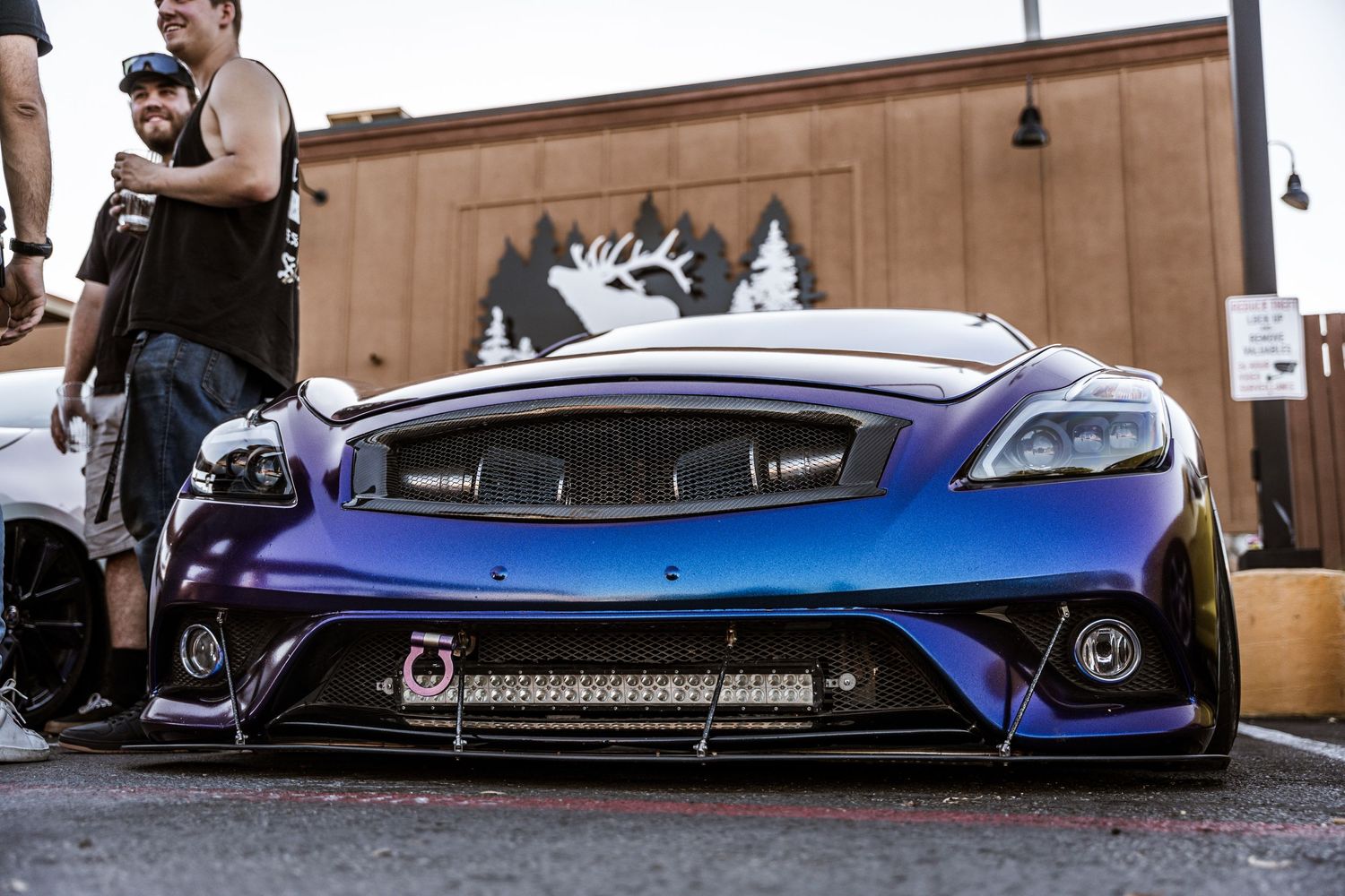 Modified blue sports car with custom front bumper and LED lighting at a car meet.