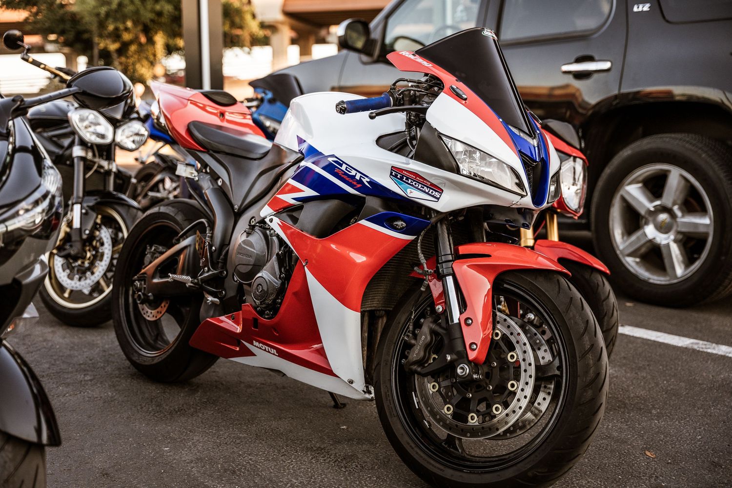 Red and white sportbike parked among other motorcycles in a parking lot.
