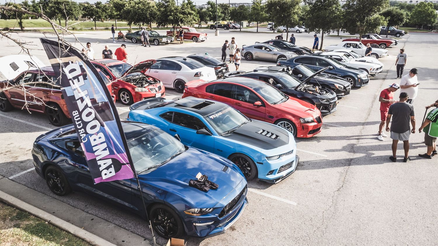 Performance cars lined up at a car show featuring muscle cars and modern sports vehicles.