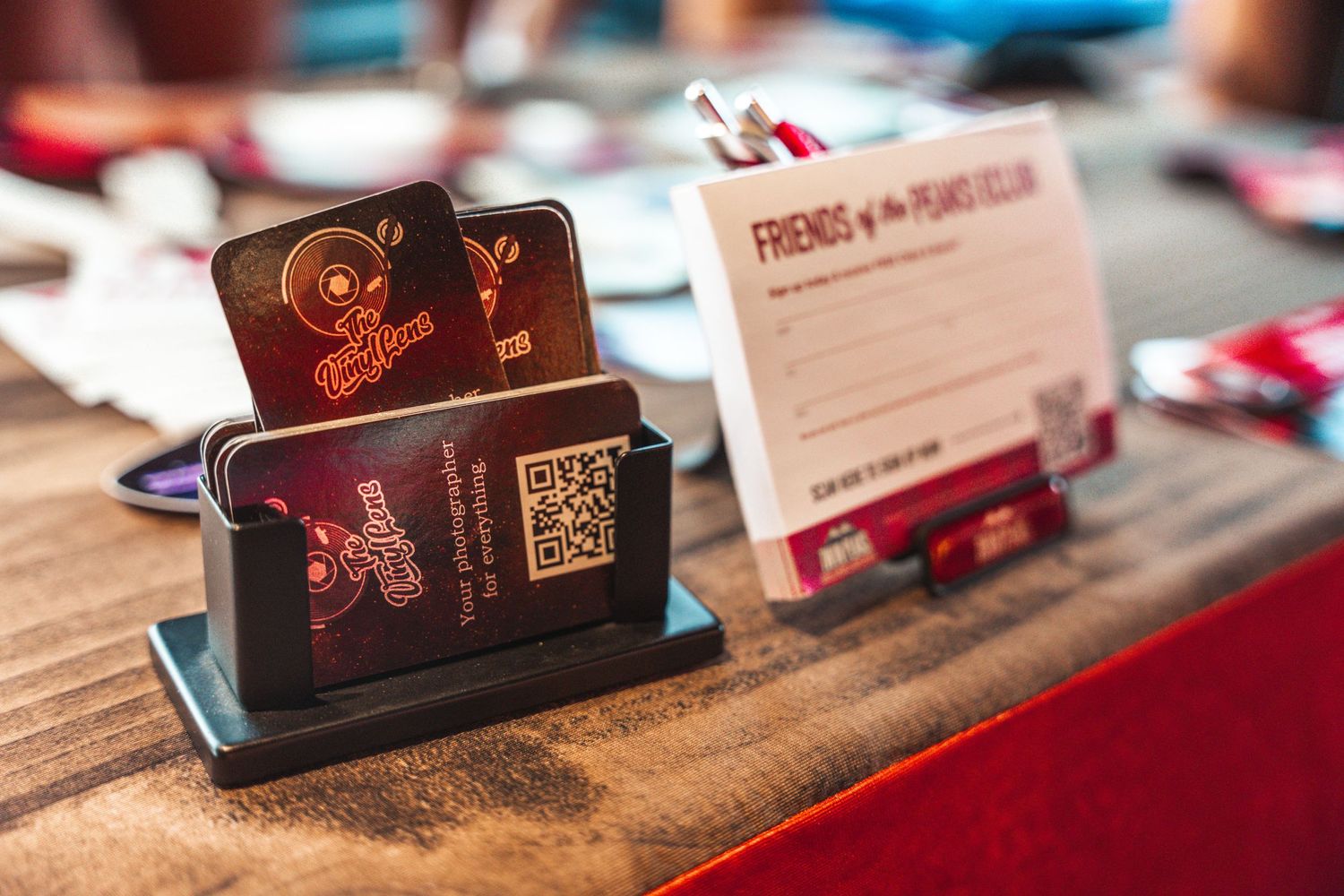 Automotive event badges and passes displayed on wooden surface with red lighting.