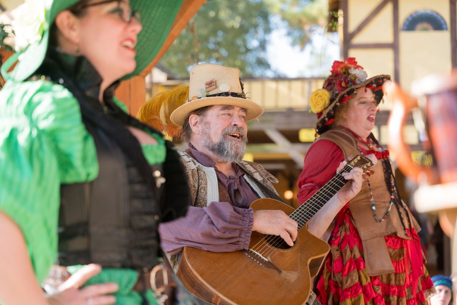 Musical performers in period costumes entertain guests at a Renaissance festival.