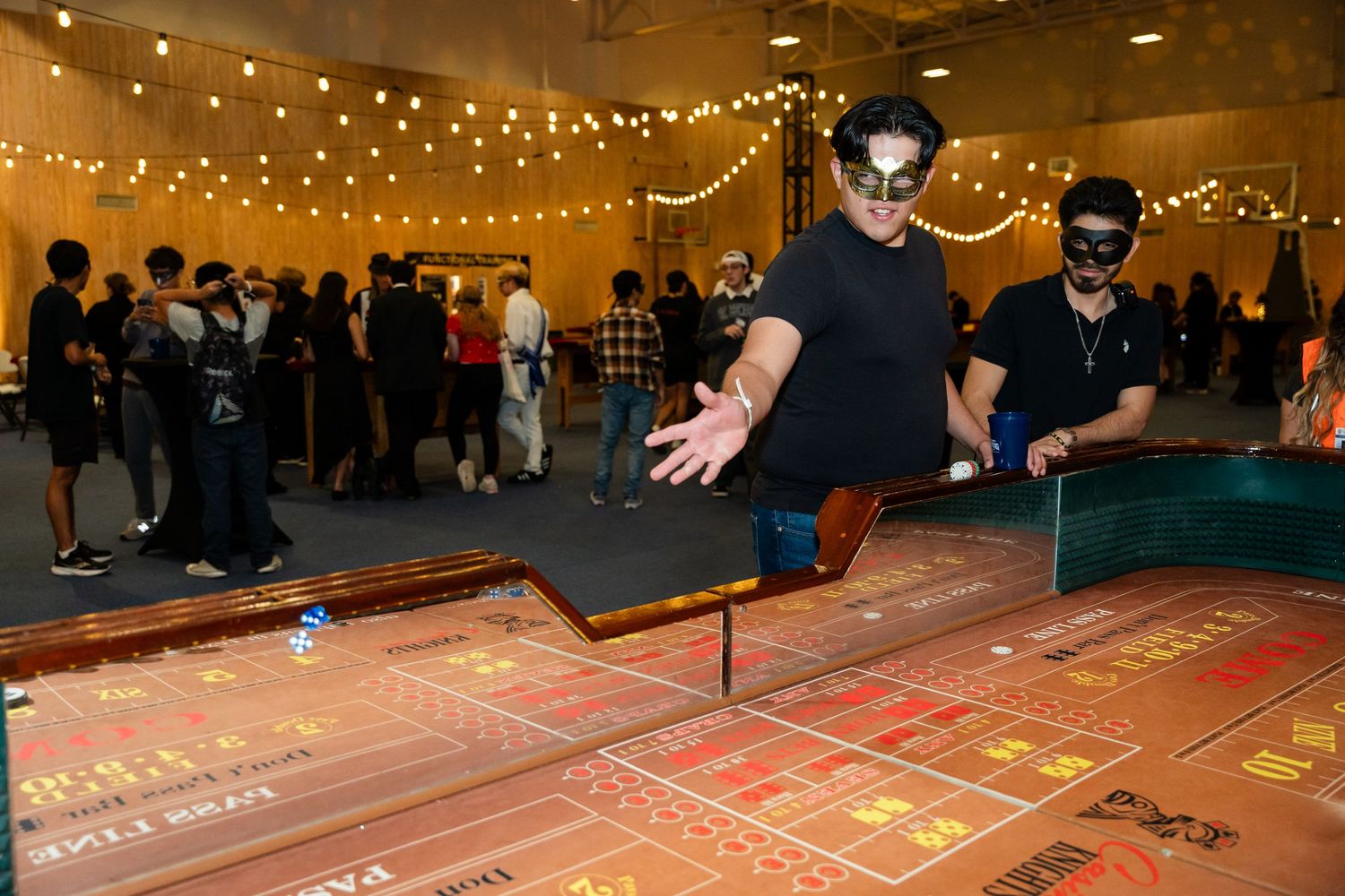 Casino craps table with string lights overhead and players placing bets.
