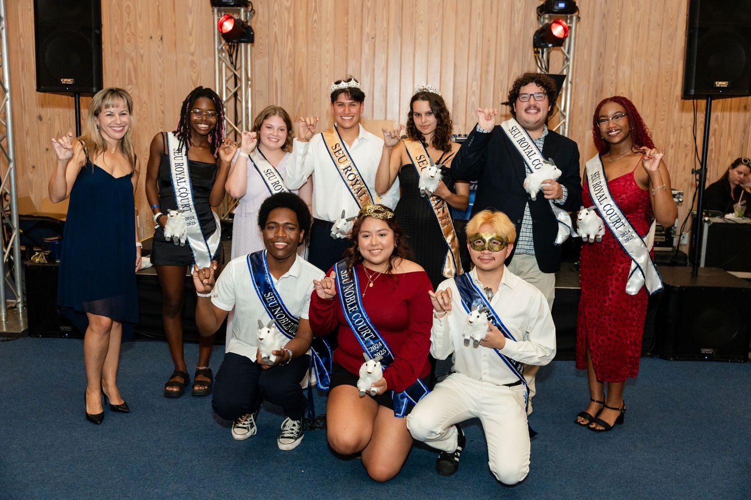 Group photo of event participants wearing formal attire and celebratory sashes.