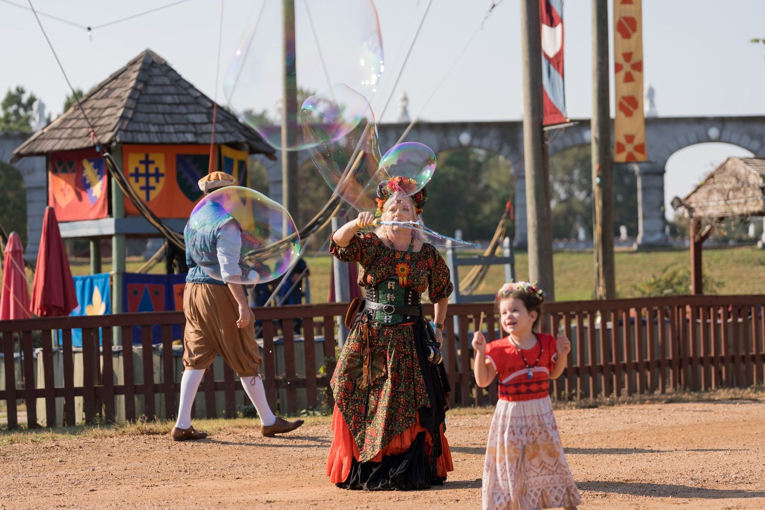Historical reenactment scene with performers in period costumes at an outdoor festival.
