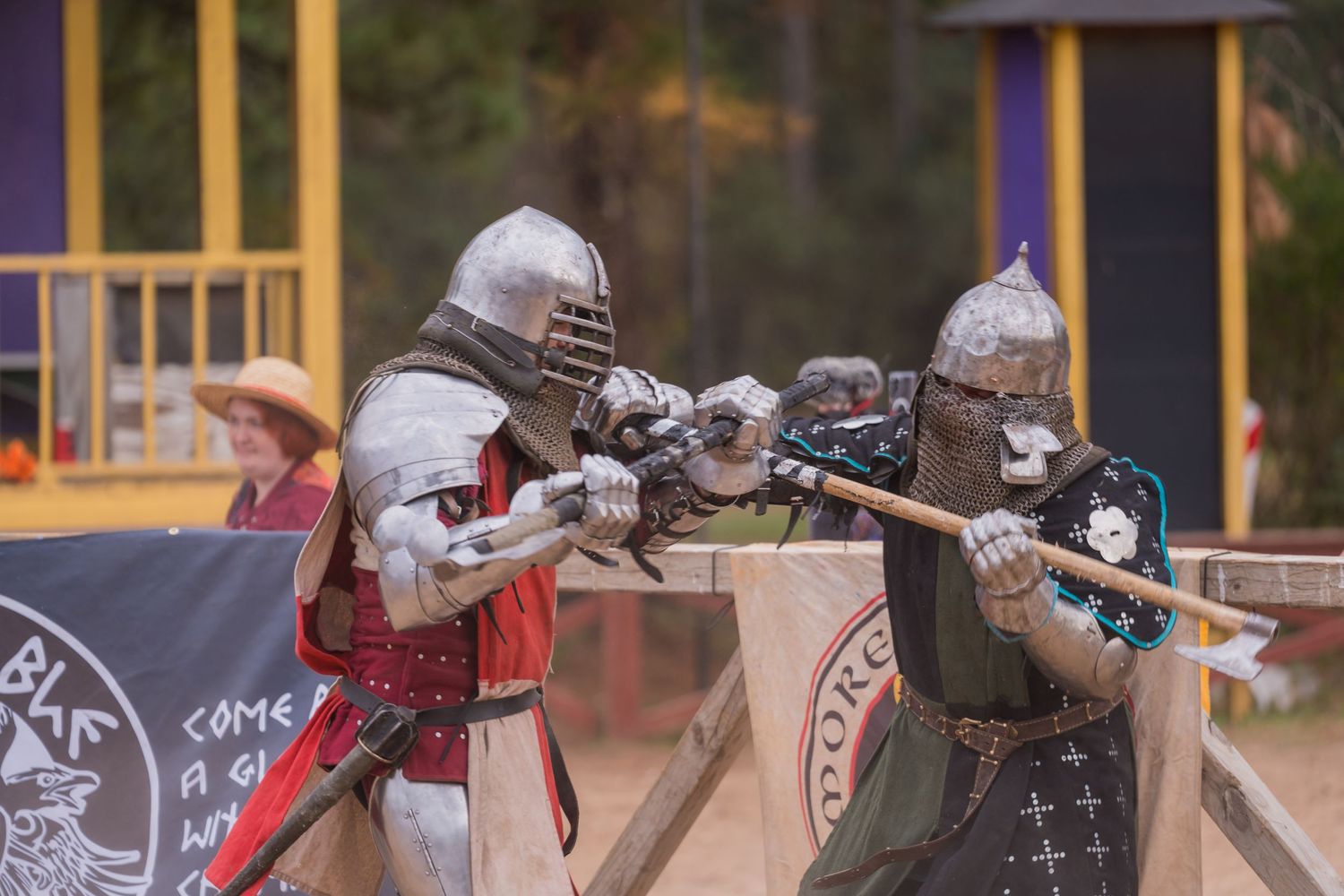 Two knights engage in sword combat during a staged renaissance fair performance.