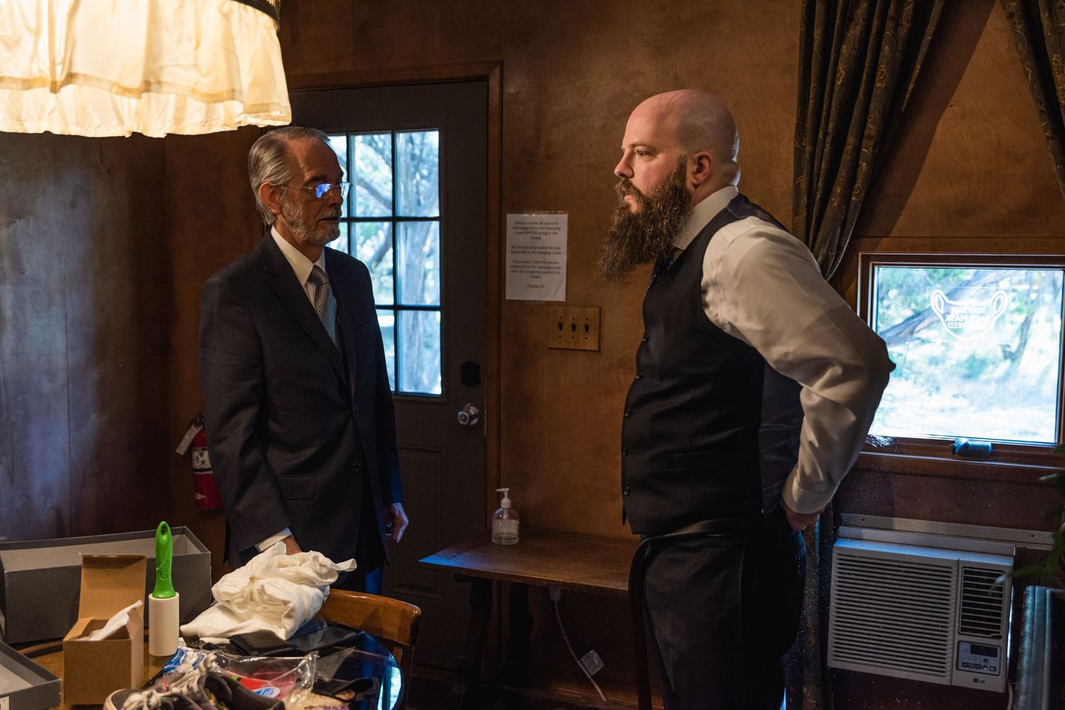 Two people having a conversation in a dimly lit rustic room.