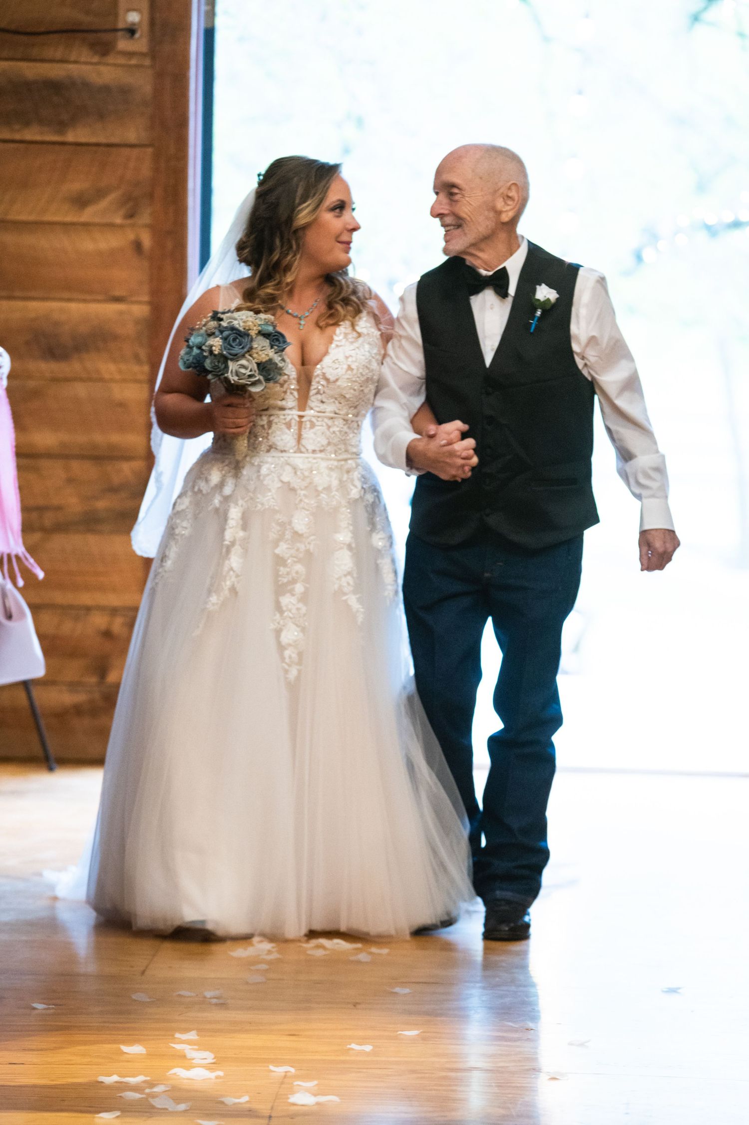 A newlywed couple walks arm in arm during their wedding ceremony in a rustic venue.