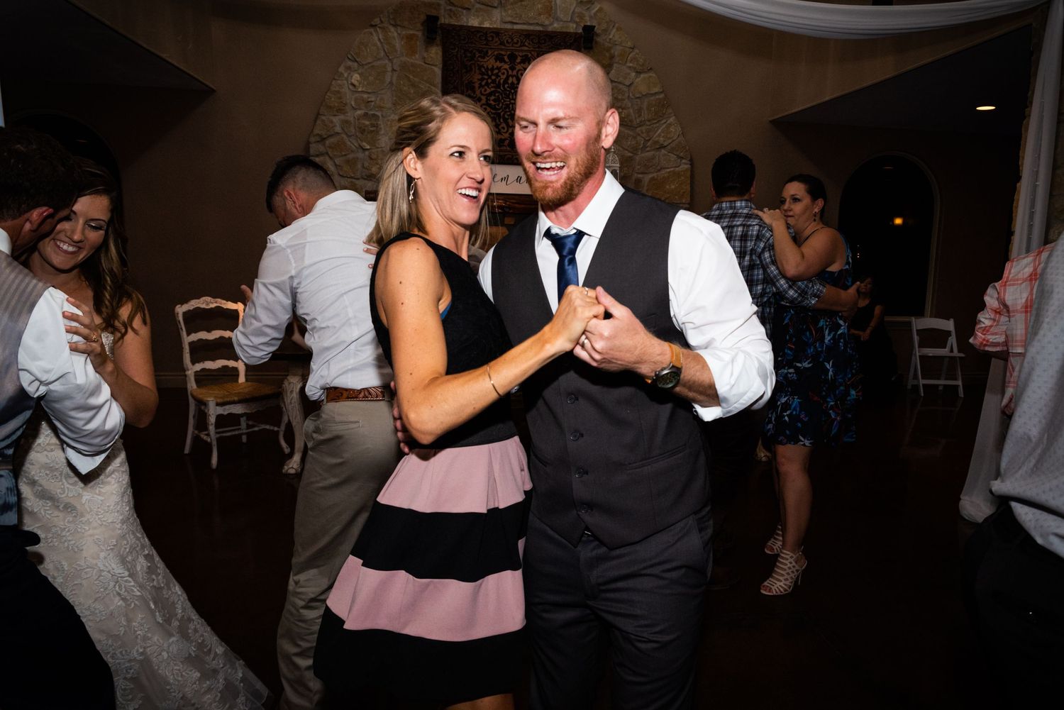 Couple dancing intimately at wedding reception in formal attire.