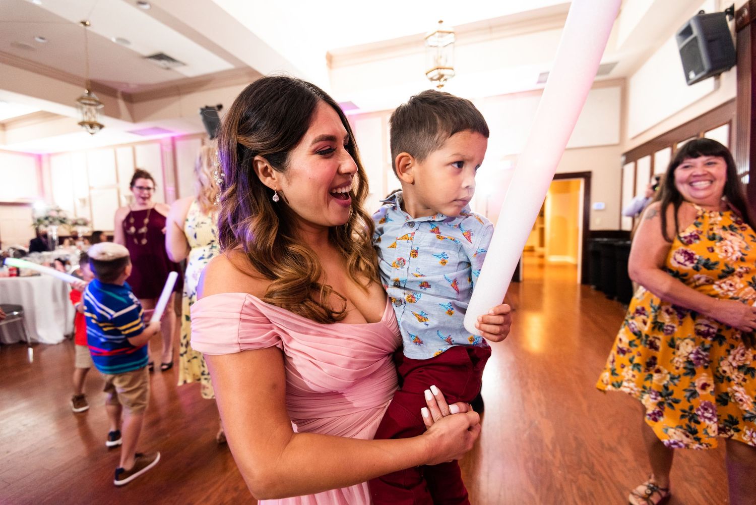 Guests enjoying festivities at an indoor celebration with warm lighting and hardwood floors.