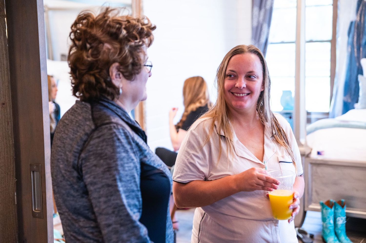 Two people chatting and enjoying drinks in casual attire at an indoor gathering.