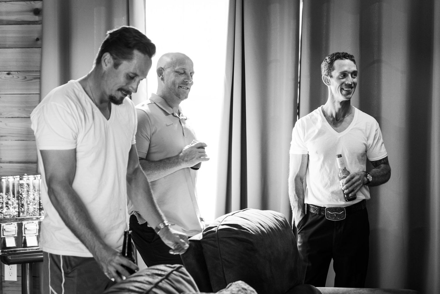 A candid black and white photo showing men in white t-shirts sharing a laugh together.
